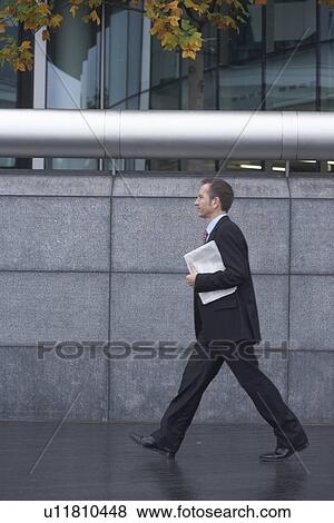 Businessman carrying paper outdoors View Large Photo Image Stock Photo - Businessman carrying paper outdoors. Fotosearch