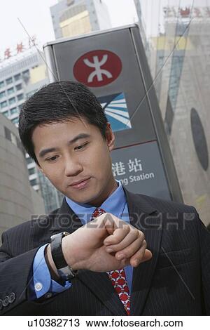Stock Image - Businessman checking watch outdoors. Fotosearch