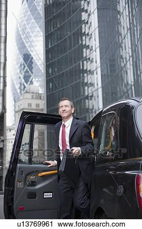 Stock Image - Businessman climbing out of taxi cab. Fotosearch