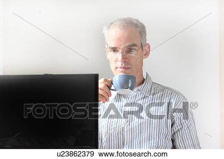 Businessman drinking coffee at computer View Large Photo Image Stock Photo - Businessman drinking coffee at computer. Fotosearch