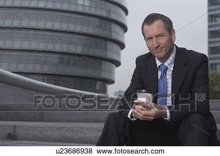 Stock Photo - Businessman drinking coffee on steps. Fotosearch