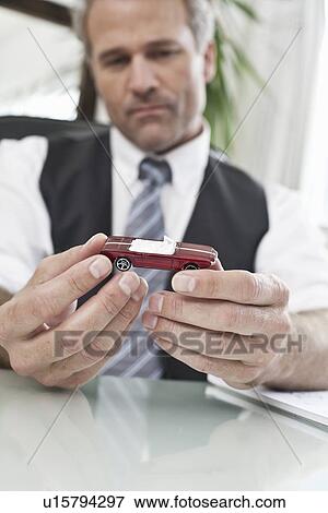 Businessman examining toy car View Large Photo Image Stock Photo - Businessman examining toy car. Fotosearch