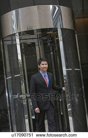 Businessman exiting revolving door View Large Photo Image Stock Image - Businessman exiting revolving door. Fotosearch