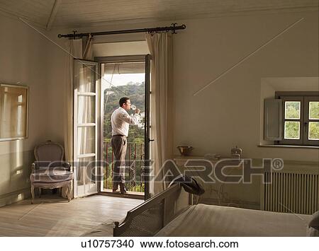 Stock Image - Businessman having wine on balcony. Fotosearch