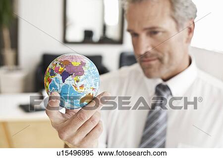 Businessman holding miniature globe View Large Photo Image Stock Photography - Businessman holding miniature globe. Fotosearch