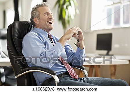 Businessman laughing at desk View Large Photo Image Stock Photo - Businessman laughing at desk. Fotosearch
