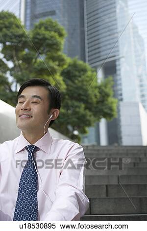 Stock Photography - Businessman listening to headphones. Fotosearch
