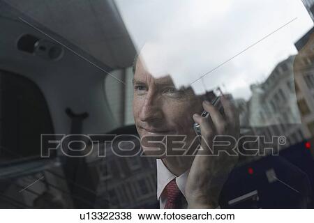 Stock Photo - Businessman on cell phone in backseat. Fotosearch