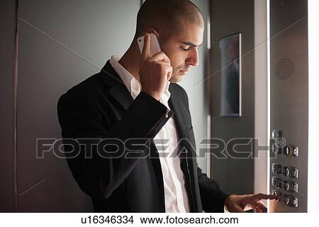 Businessman on cell phone in elevator View Large Photo Image Picture - Businessman on cell phone in elevator. Fotosearch
