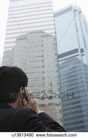 Stock Image - Businessman on cell phone on city street. Fotosearch