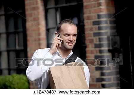 Stock Photo - Businessman on cell phone on city street. Fotosearch