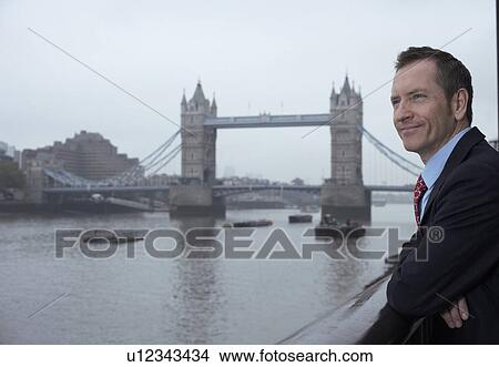 Businessman overlooking urban river View Large Photo Image Picture - Businessman overlooking urban river. Fotosearch