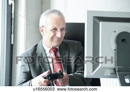 Stock Image - Businessman playing video games at desk. Fotosearch