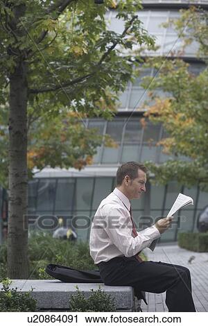 Businessman reading newspaper in park View Large Photo Image Stock Image - Businessman reading newspaper in park. Fotosearch