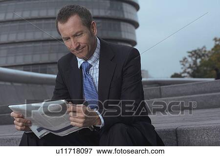 Businessman reading newspaper on steps View Large Photo Image Stock Photo - Businessman reading newspaper on steps. Fotosearch