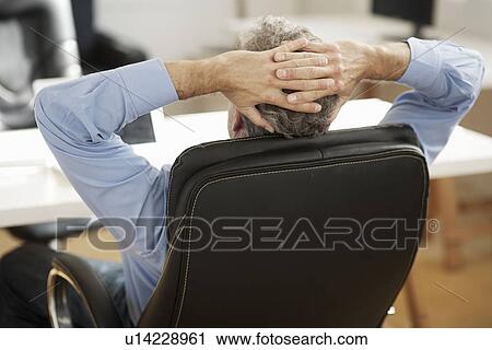 Stock Image - Businessman relaxing at desk. Fotosearch