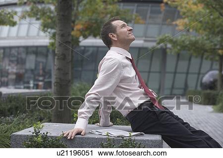 Stock Image - Businessman relaxing in urban park. Fotosearch