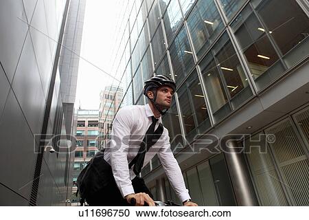 Stock Image - Businessman riding bicycle in city. Fotosearch