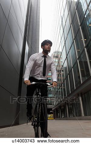 Stock Image - Businessman riding bicycle in city. Fotosearch