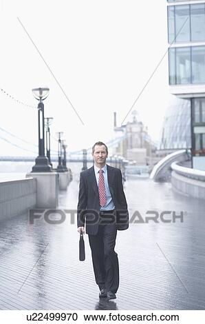 Stock Image - Businessman rolling luggage outdoors. Fotosearch