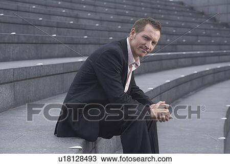 Stock Image - Businessman sitting on city steps. Fotosearch