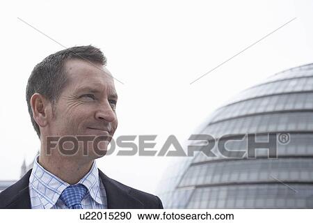 Businessman standing by urban building View Large Photo Image Stock Image - Businessman standing by urban building. Fotosearch