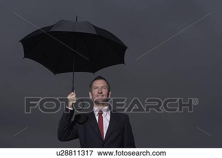 Businessman standing under umbrella View Large Photo Image Stock Photo - Businessman standing under umbrella. Fotosearch