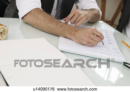 Stock Photograph - Businessman taking notes at desk. Fotosearch