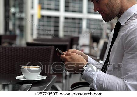Businessman using cell phone at cafe View Large Photo Image Stock Photo - Businessman using cell phone at cafe. Fotosearch
