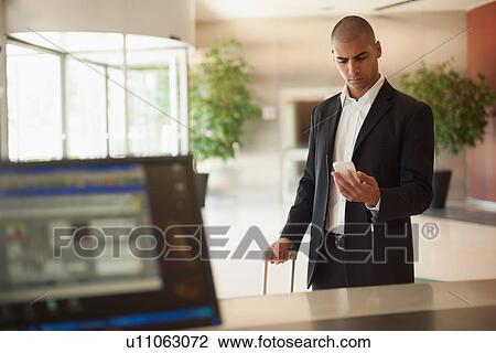 Businessman using cell phone in lobby View Large Photo Image Stock Image - Businessman using cell phone in lobby. Fotosearch