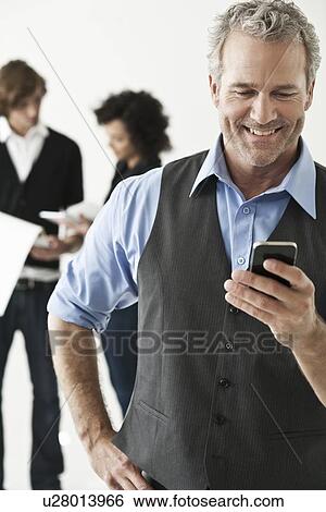 Businessman using cell phone in office View Large Photo Image Stock Photograph - Businessman using cell phone in office. Fotosearch