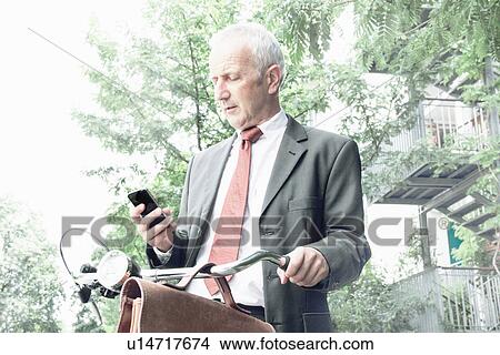 Businessman using cell phone on bicycle View Large Photo Image Picture - Businessman using cell phone on bicycle. Fotosearch