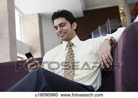 Businessman using cell phone on sofa View Large Photo Image Stock Image - Businessman using cell phone on sofa. Fotosearch