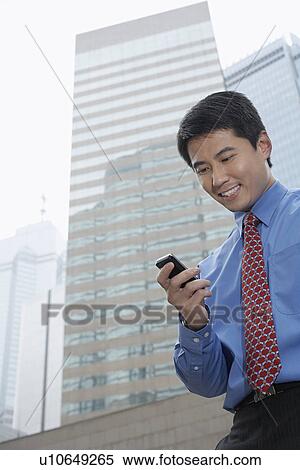 Businessman using cell phone outdoors View Large Photo Image Stock Photography - Businessman using cell phone outdoors. Fotosearch