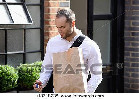Businessman using keys on city street View Large Photo Image Stock Photography - Businessman using keys on city street. Fotosearch