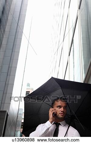 Stock Photo - Businessman walking under umbrella. Fotosearch