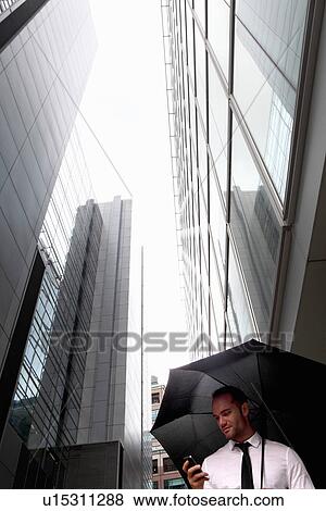 Stock Photo - Businessman walking under umbrella. Fotosearch