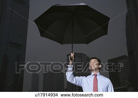 Businessman with umbrella on city street View Large Photo Image Picture - Businessman with umbrella on city street. Fotosearch