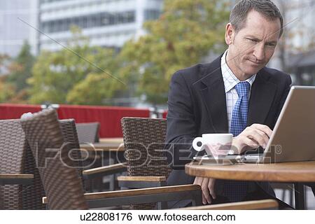Stock Photograph - Businessman working on laptop at cafe. Fotosearch