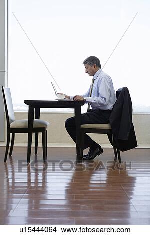 Picture - Businessman working on laptop in cafe. Fotosearch