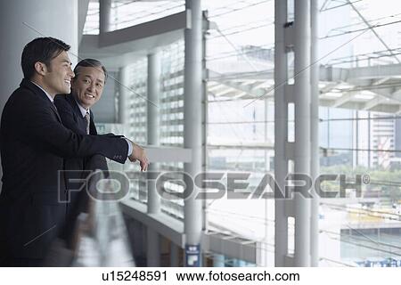 Stock Image - Businessmen leaning on banister. Fotosearch