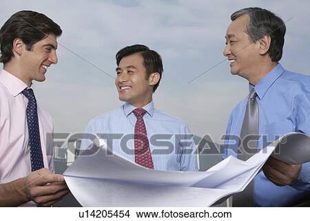 Businessmen reading blueprints together View Large Photo Image Picture - Businessmen reading blueprints together. Fotosearch