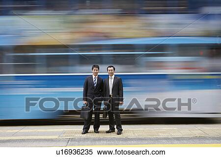 Businessmen standing by blurred bus View Large Photo Image Stock Photography - Businessmen standing by blurred bus. Fotosearch