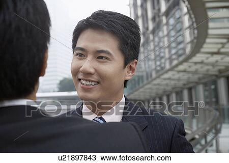 Businessmen talking on walkway View Large Photo Image Stock Image - Businessmen talking on walkway. Fotosearch