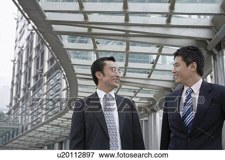Stock Photo - Businessmen talking on walkway. Fotosearch
