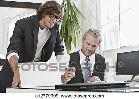Businessmen working together at desk View Large Photo Image Stock Photo - Businessmen working together at desk. Fotosearch
