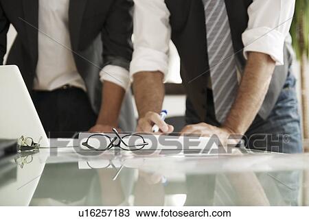 Stock Image - Businessmen working together in office. Fotosearch