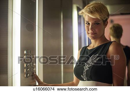 Picture - Businesswoman pressing elevator button. Fotosearch