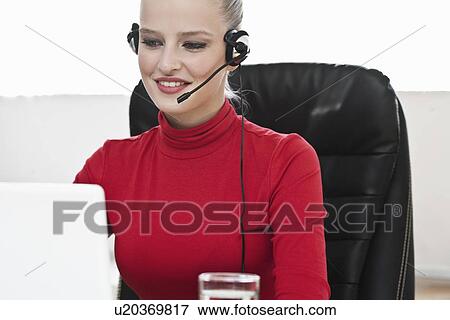 Businesswoman wearing headset in office View Large Photo Image Stock Photo - Businesswoman wearing headset in office. Fotosearch