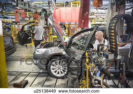 Stock Photo - Car assembly workers fitting doors to cars on production line in car factory. Fotosearch